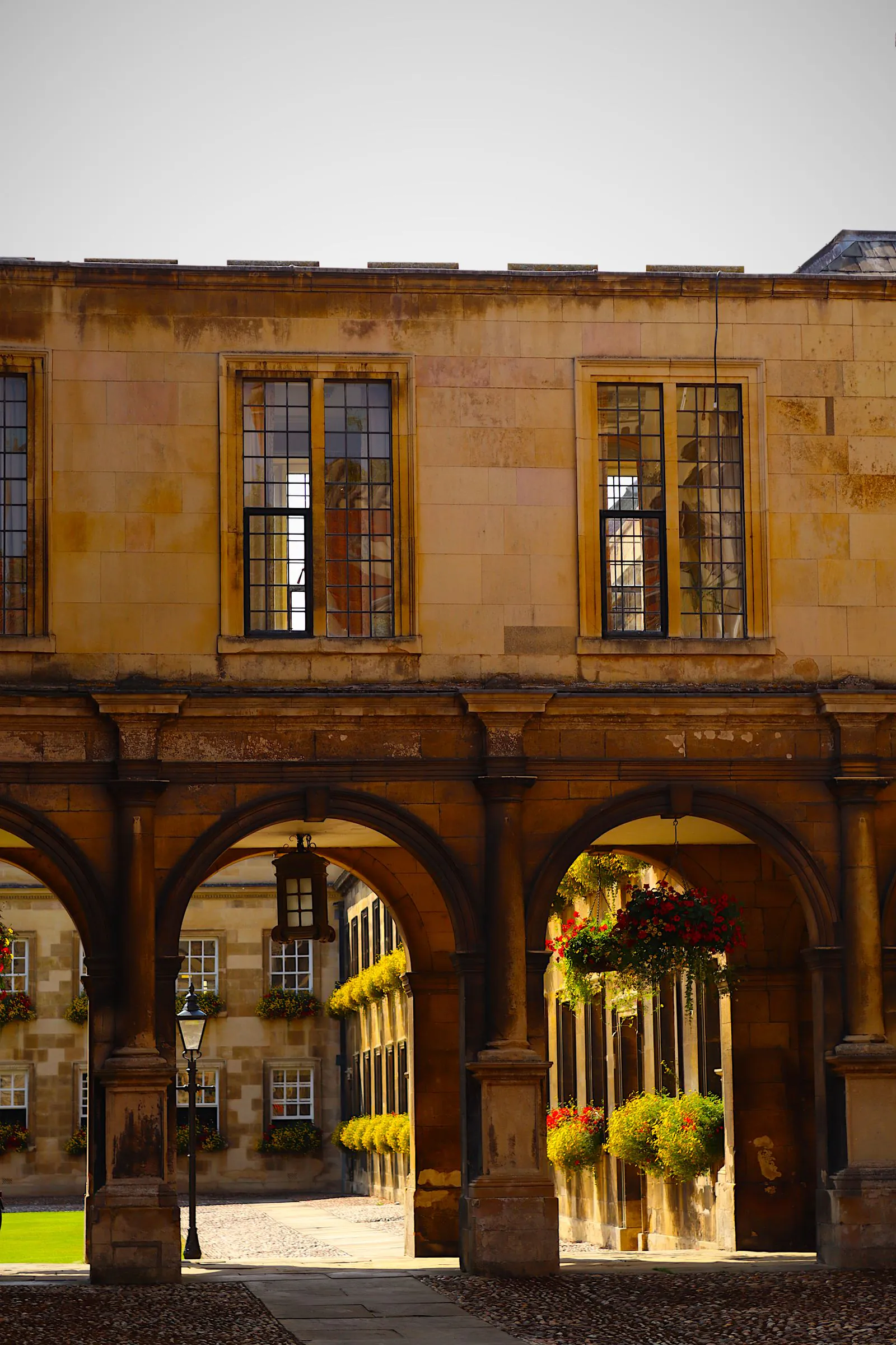 Portrait-format stock photograph of Oxford collegiate arches in warm sandstone-coloured masonry, exact stone type unverified, shown at courtyard scale.
