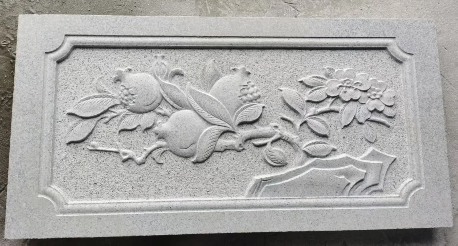 Naturalistic high-relief stone panel of floral and fruit forms.