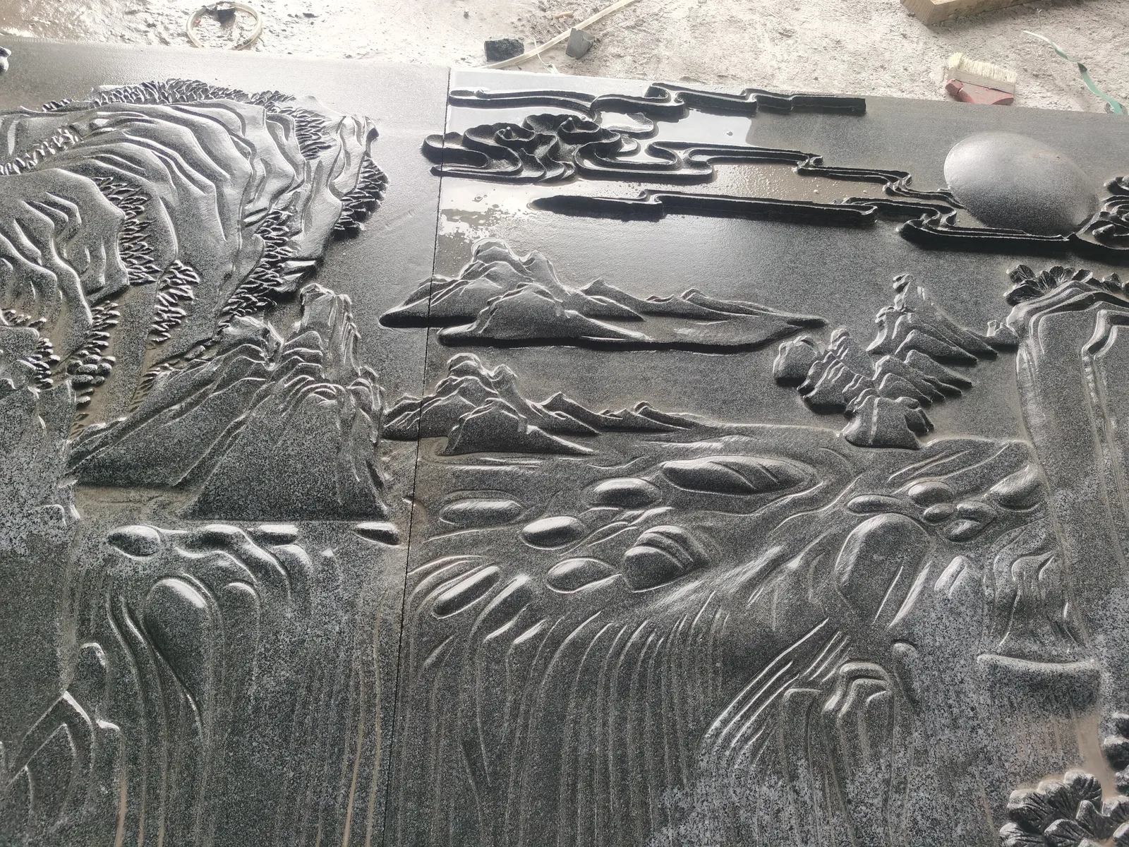 Layered landscape scene carved in stone relief.
