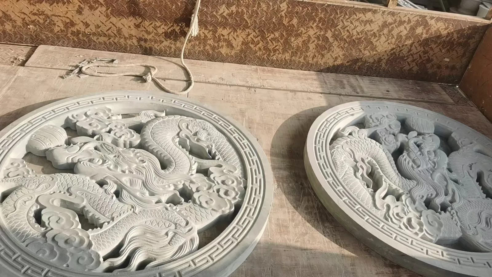 Circular stone relief panel carved with two interlaced dragons and deep undercutting.